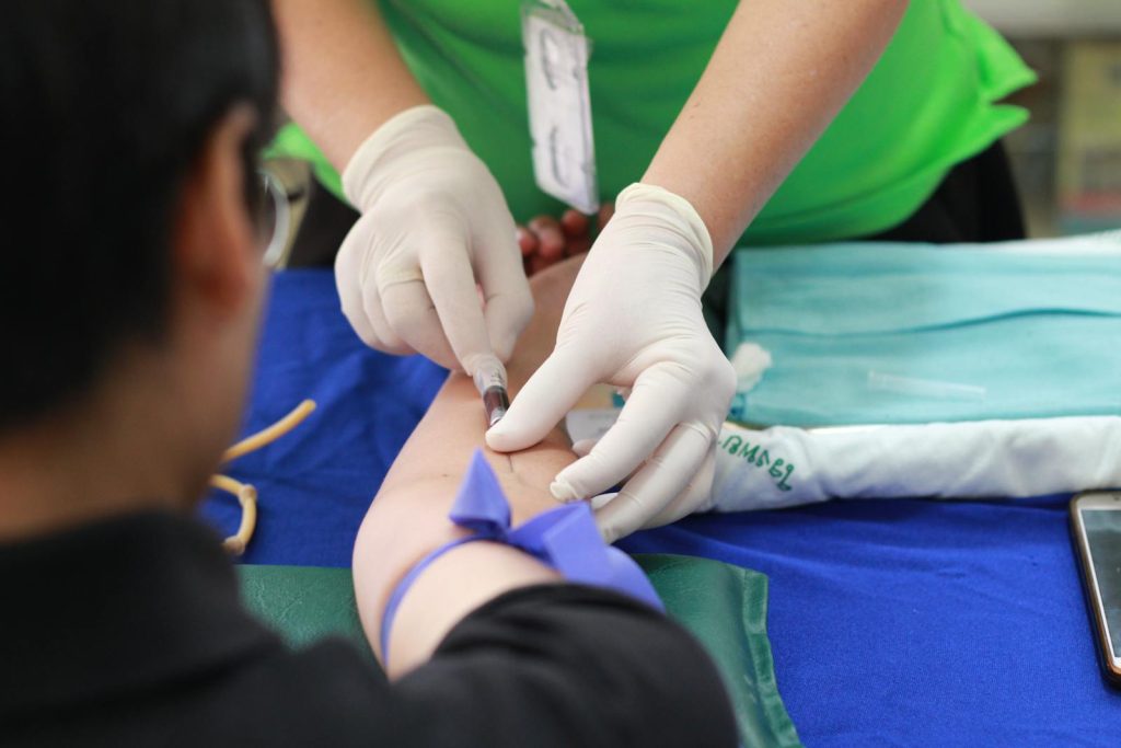 Eine medizinische Fachkraft, die einem Patienten während eines medizinischen Eingriffs eine Injektion in den Arm verabreicht.