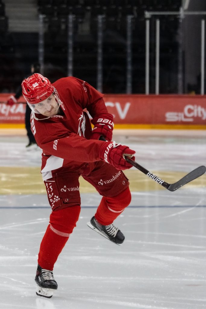 ein Mann in einer roten Uniform, der auf einer Eisbahn Schlittschuh läuft